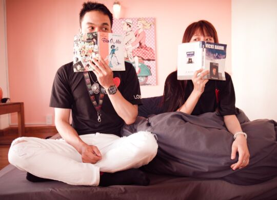 couple-holding-books-sitting-on-bed-1057015