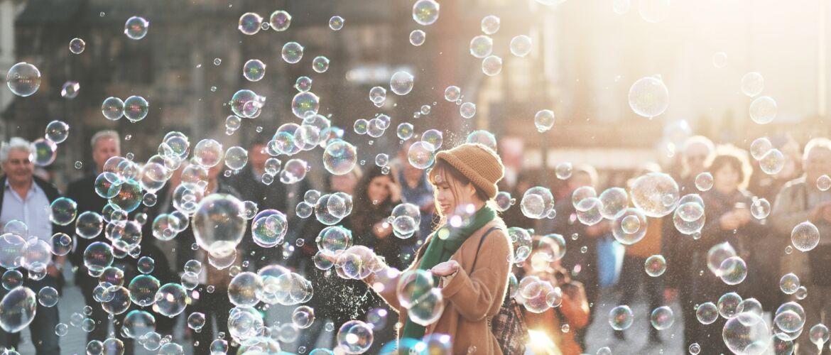 A woman is standing in front of many bubbles.