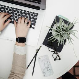 A person sitting at a desk with a laptop and pen.