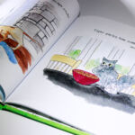 CoopCatsS5 A book with an image of a cat and a pencil.