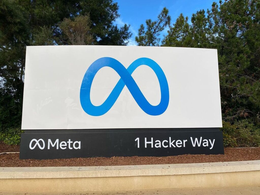 Meta sign at the company’s Menlo Park headquarters, showing the Meta logo and “1 Hacker Way.”
